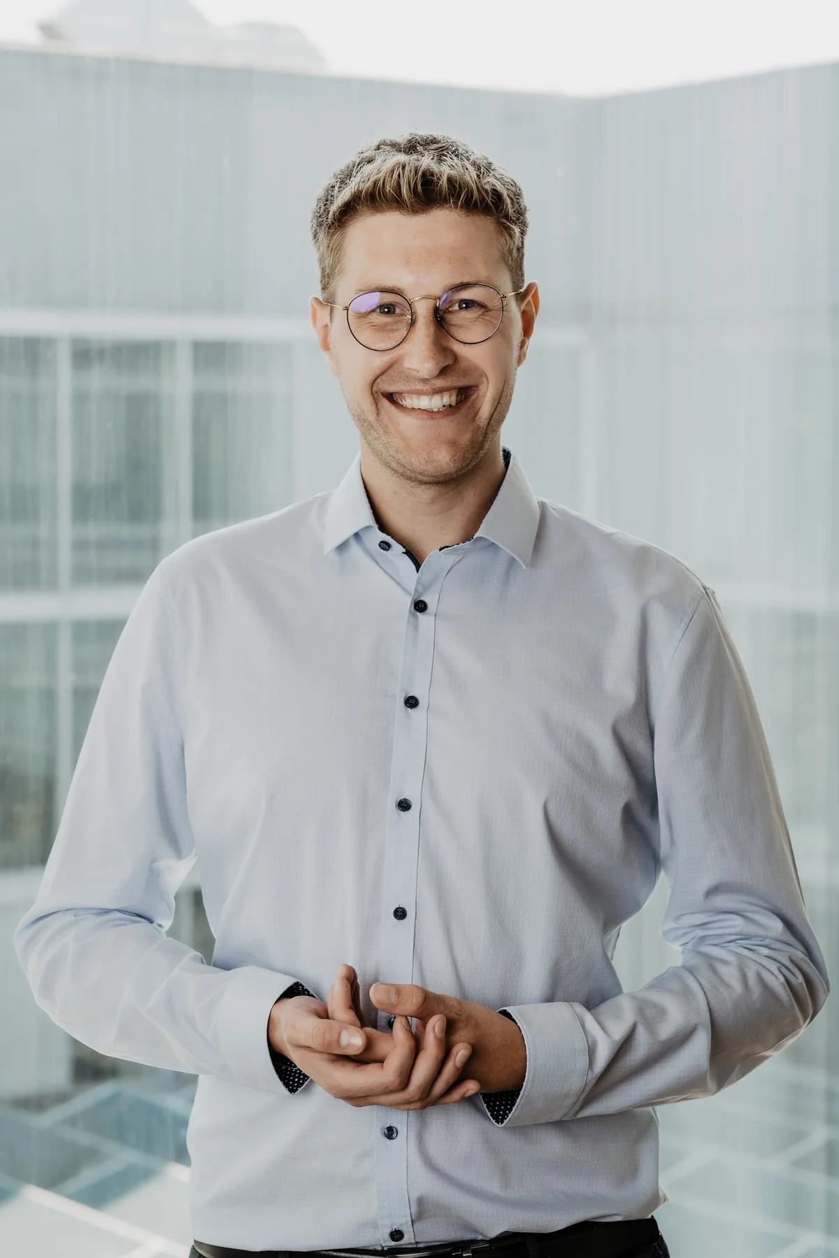 Jannik Reinhard im hellen Büro, im Hemd und mit einem offenen Lächeln.