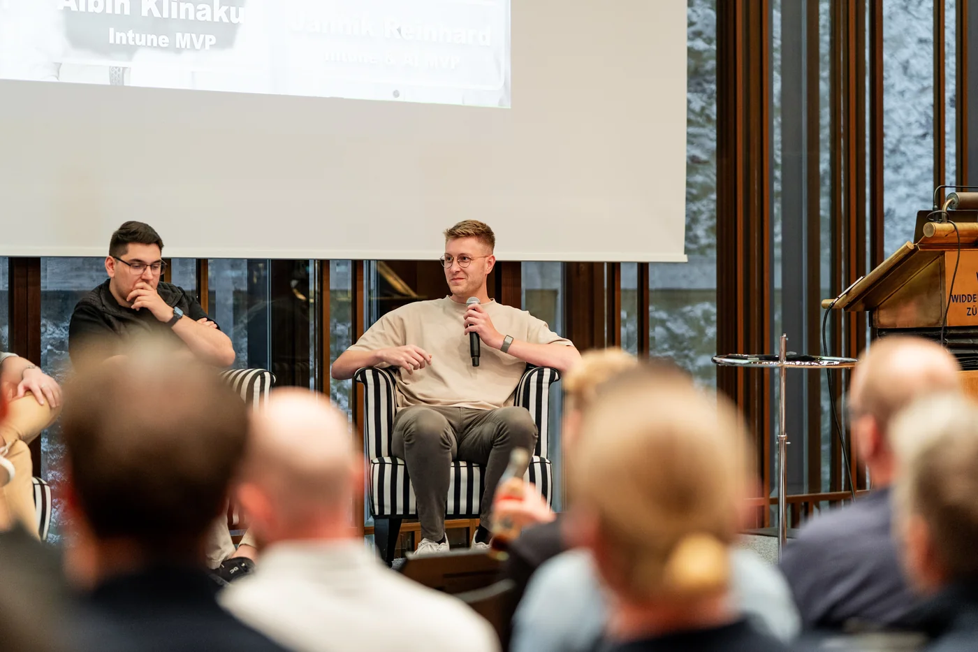 Jannik Reinhard mit Mikrofon bei einem Podiumsgespräch vor Publikum in Zürich.
